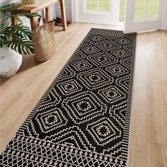 a black and white area rug on the floor in front of a window with potted plants