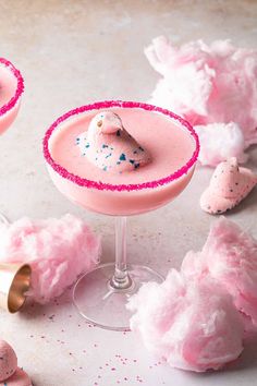 two pink cocktails with sprinkles on the rim and one filled with candy