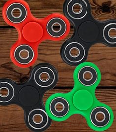 three different colored fidgets sitting next to each other on top of a wooden table