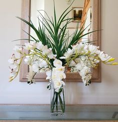 a vase filled with white flowers sitting on top of a table next to a mirror