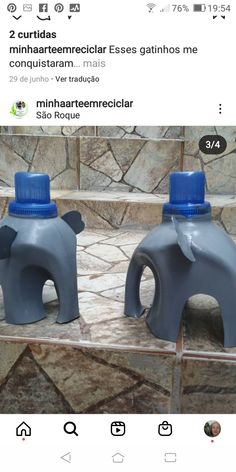 two plastic elephants sitting on top of a tiled floor next to each other in front of a stone wall