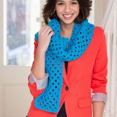 a smiling woman wearing a blue crochet scarf and red blazer with black pants