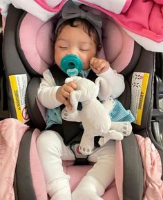 a baby in a car seat with a pacifier