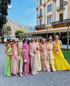 a group of women standing next to each other in front of a building with mountains behind them