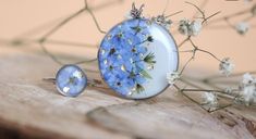 two rings with blue flowers on them sitting on a piece of wood next to white flowers