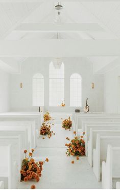 an empty white church with flowers on the pews