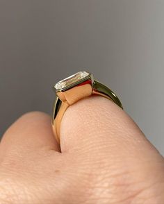 a close up of a person's hand wearing a ring with a diamond on it