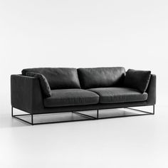 a black leather couch sitting on top of a white floor next to a metal frame