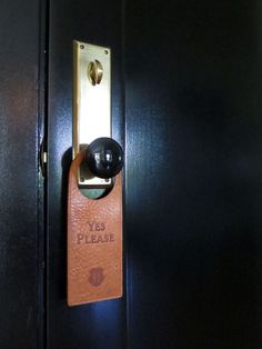 a door handle with the words yes please on it and a leather tag attached to it