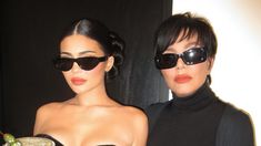 two women in black clothing and sunglasses standing next to each other