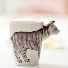 a coffee cup with a drawing of a cat on it's front and side