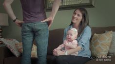 a woman holding a baby while sitting on top of a couch next to a man