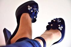 a woman's feet wearing blue shoes with white flowers on the toes and heel