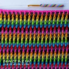 a crocheted blanket is shown with a knitting needle next to it and the colors of the yarn are multicolored