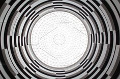 looking up into the center of a circular window in an office building with geometric patterns