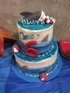 a three tiered cake with a shark on it's side and the number six