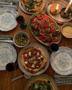 a table topped with plates and pizza covered in toppings next to a lit candle