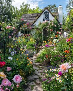 a garden filled with lots of flowers next to a house