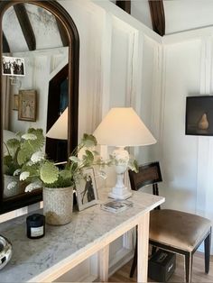 a vanity with a mirror, lamp and pictures on the wall in front of it