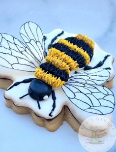 two decorated cookies with black and yellow designs on them, one has a bee in the middle