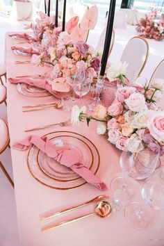 the table is set with pink and gold place settings