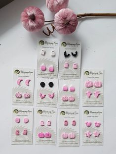 the pink and black earrings are on display next to some yarn balls with flowers in them