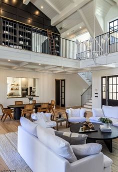 a large open floor plan living room with high ceilings and white furniture in the center