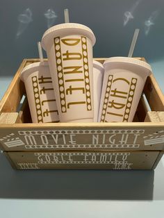 three cups in a wooden box with the word drink written on them and two straws sticking out of each cup