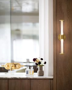 a vase with flowers sitting on a counter next to a mirror