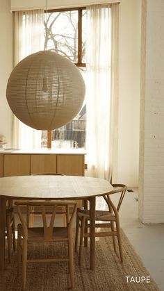 a table and chairs in front of a window with a large light fixture hanging from the ceiling