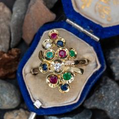 This wonderful ring features two (2) round brilliant cut diamonds, three (3) round mixed cut emeralds, rubies and sapphires, bead set in individual dishes. The ring measures 23.2mm at the top, rises 8.6mm above the finger, tapering to 1.7mm wide and 1.4mm thick at the base of the shank. This ring is currently a size 7.25. Multi-stone Emerald Diamond Ring As Gift, Yellow Gold Multi-stone Emerald Birthstone Ring, Round Multi-stone Diamond Emerald Ring, Emerald Multi-stone Round Cut Ring, Multi-stone Round Cut Emerald Ring, Round Cut Multi-stone Emerald Ring, Fine Jewelry Multi-stone Emerald Diamond Ring, Round Multi-stone Emerald Ring, Emerald Multi-stone Birthstone Ring Gift