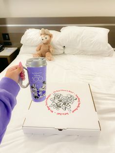 a person is holding a cup in front of a box on a bed