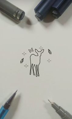 some pens are laying on top of a piece of paper with a drawing of a deer