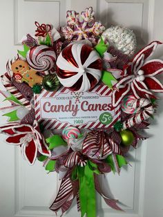 a candy cane wreath hanging on the front door with christmas decorations and candies around it