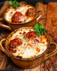 two brown bowls filled with pizza on top of a wooden cutting board next to each other