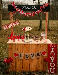 a wooden table topped with red and white flowers next to a sign that says love