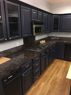 an empty kitchen with black cabinets and wood flooring is seen in this image from the front view