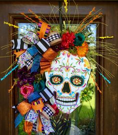 a colorful wreath with a skull and flowers on the front door for day of the dead