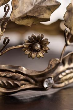 a metal object with a flower and leaves on it's side, sitting on a table