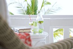 a table with a book, drink and cell phone on it next to a window