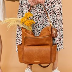 a woman holding a brown purse with flowers in it