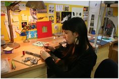 a woman sitting at a desk with lots of jewelry on her hands and looking down