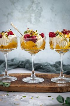 three desserts in glasses on a wooden tray