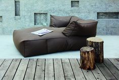 a large brown couch sitting on top of a wooden floor next to a tree stump