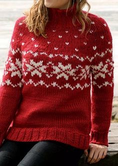 a woman sitting on a bench wearing a red sweater with white snowflakes