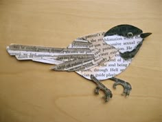 a bird made out of newspaper sitting on top of a wooden table