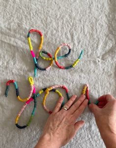 a person is writing the word love with colorful bracelets on top of a white towel