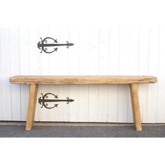 a wooden bench sitting next to a wall with two hooks on it's sides