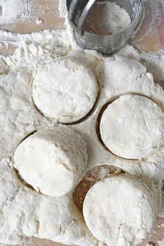 four uncooked pizza doughs sitting on top of a floured surface next to a measuring cup