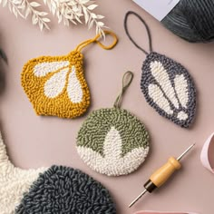 three crocheted ornaments on a pink surface with yarn and scissors next to them